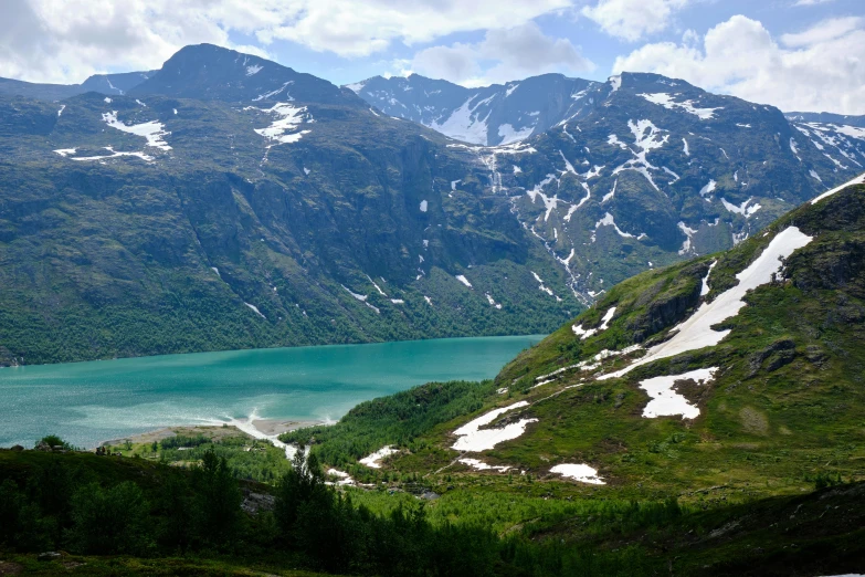 a lake surrounded by snow and mountains with trees on it