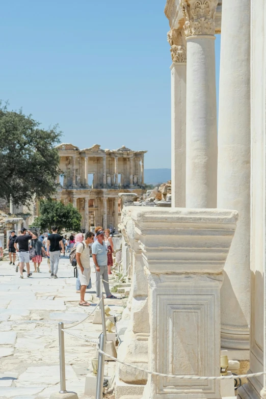 a group of people that are walking around near some columns