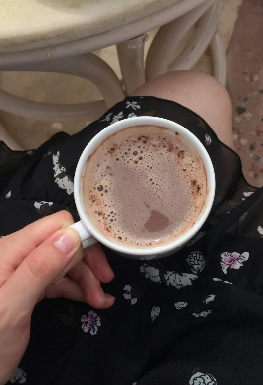 a person holding up a cup of coffee