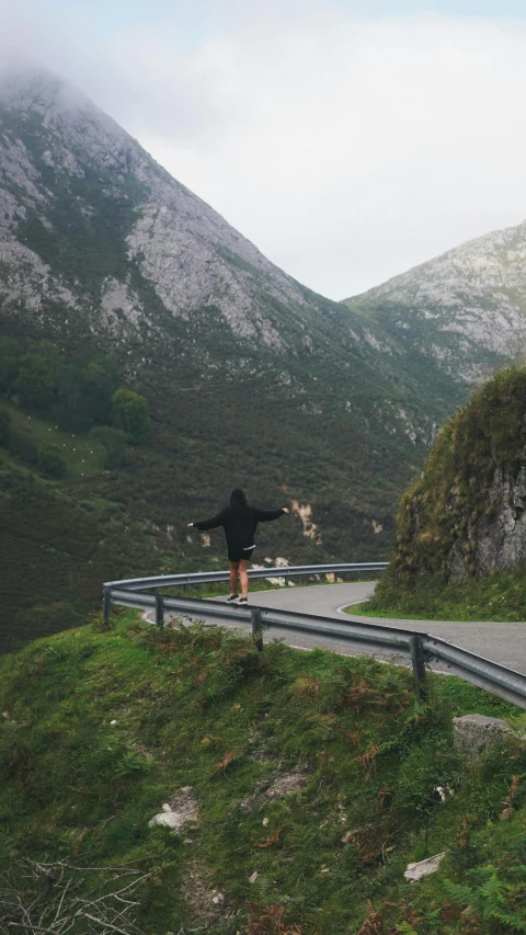 man on road doing skateboard stunt near mountain top