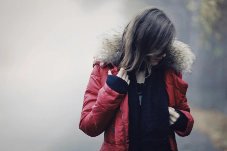 a person standing and looking down with a red jacket on