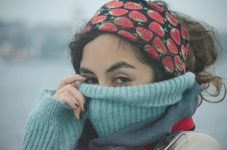 a woman is holding her scarf over her face