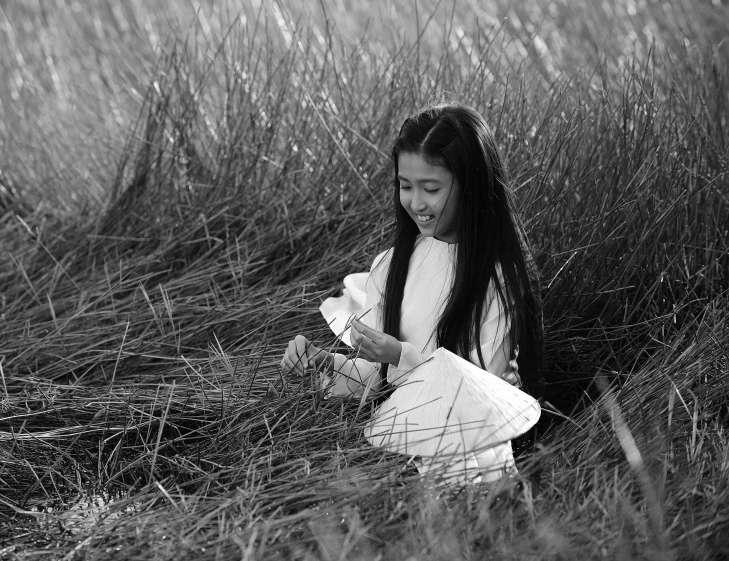 a  sitting in a grassy field with her hands together