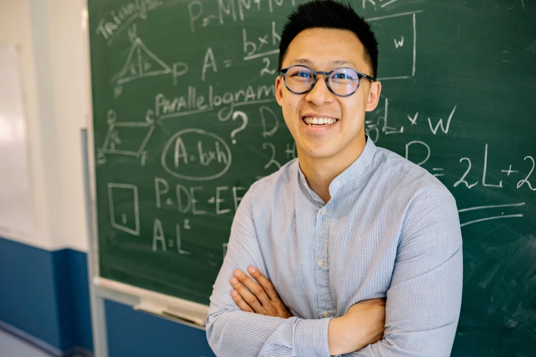 a guy in front of a chalkboard smiles