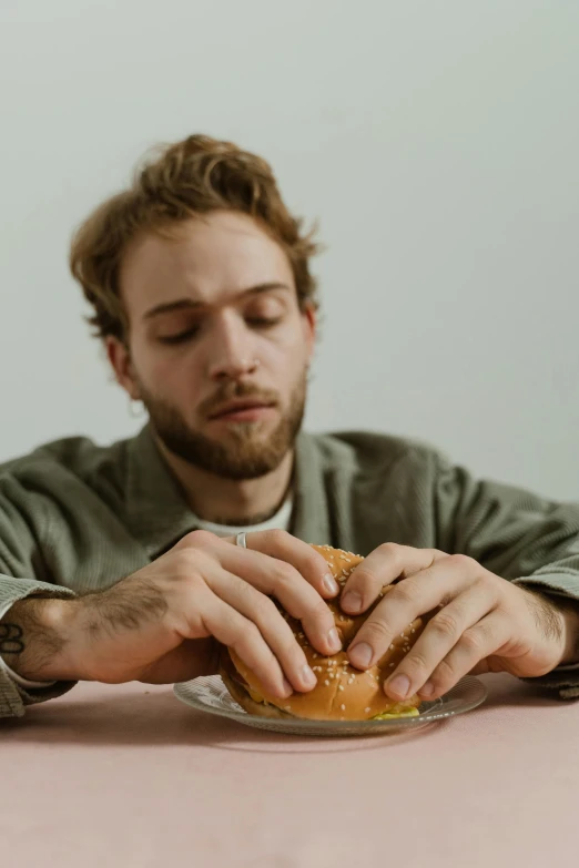 a man sitting at a table looking at a burger