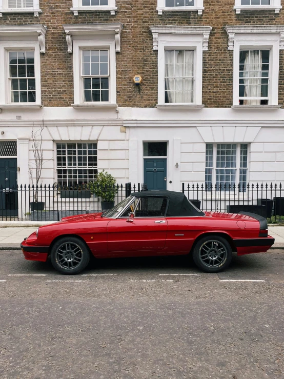 a red car is parked on the side of the road