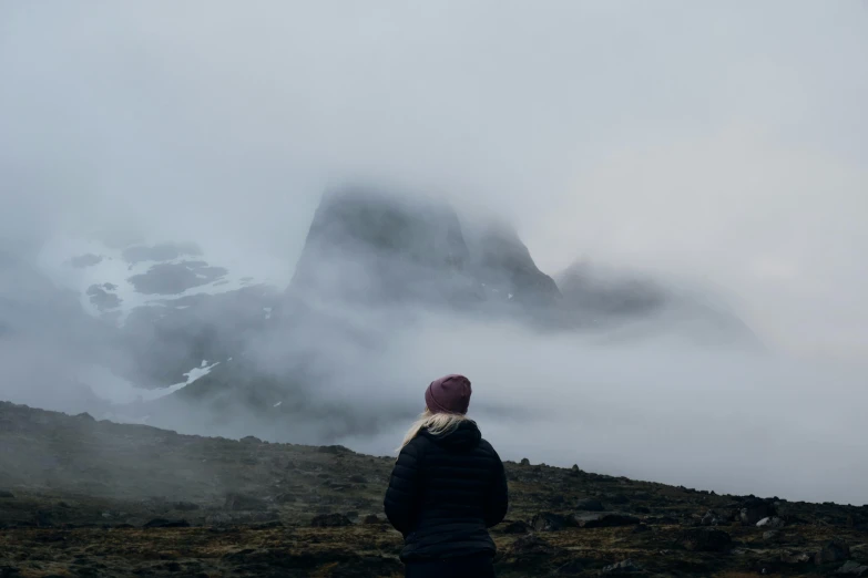 a woman with a red hat stands on a rocky hill