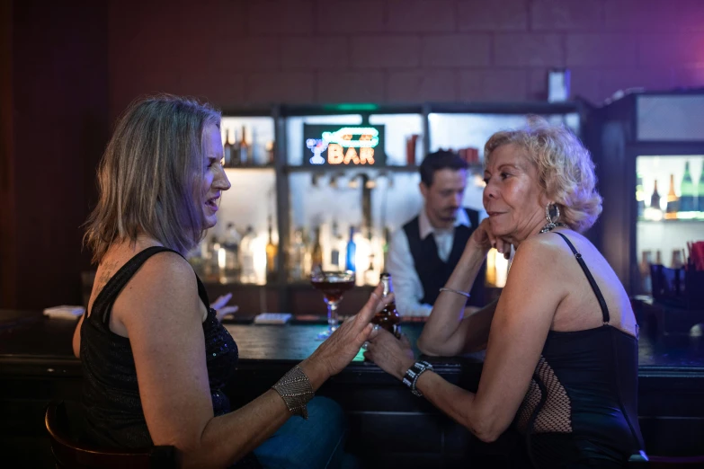 a couple of women sit on the bar next to each other