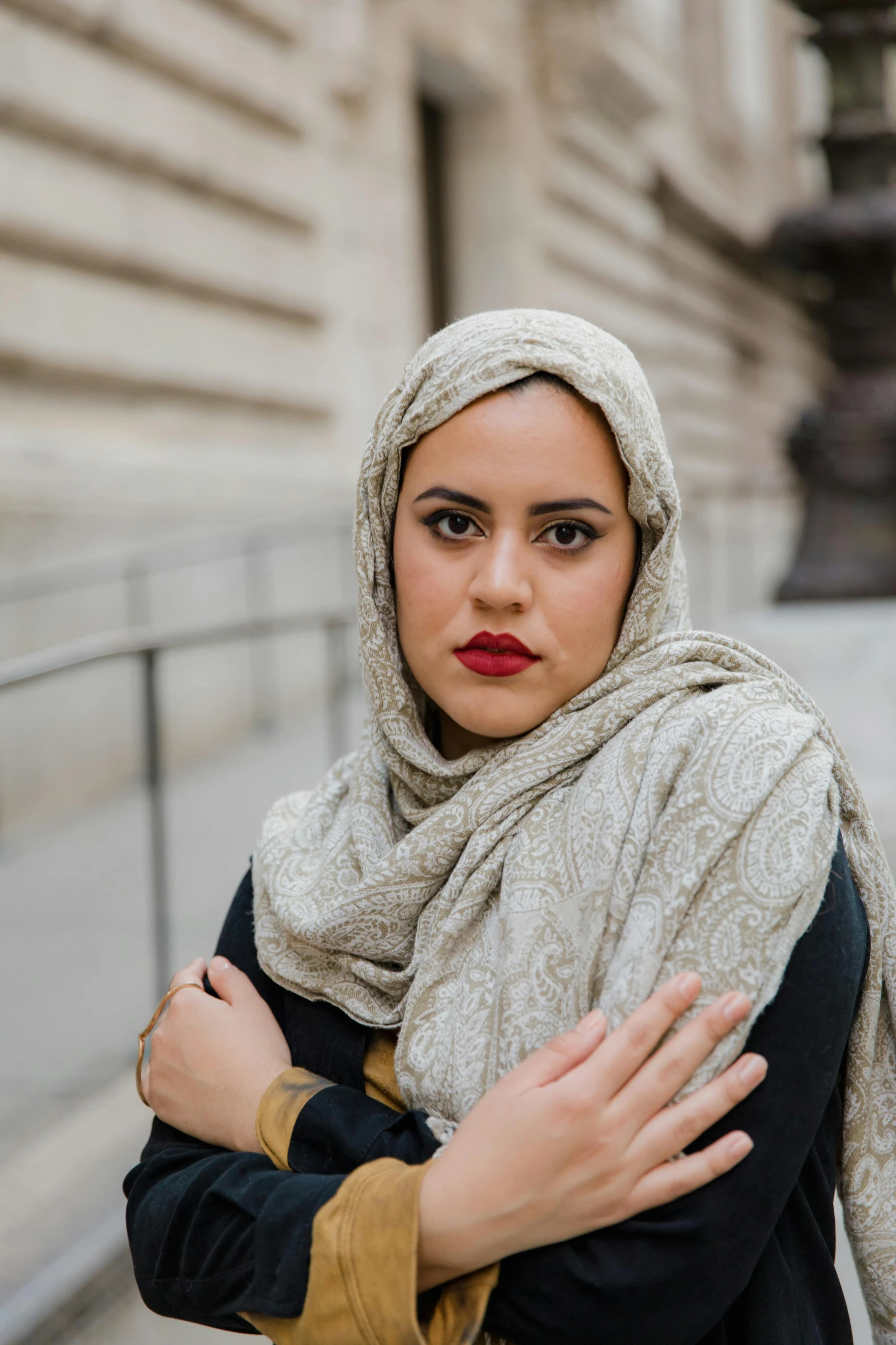 a woman with her arms crossed, posing in front of a building