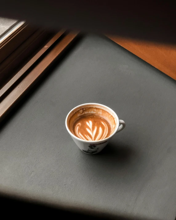 cappuccino on gray placemat, with light reflecting off the window