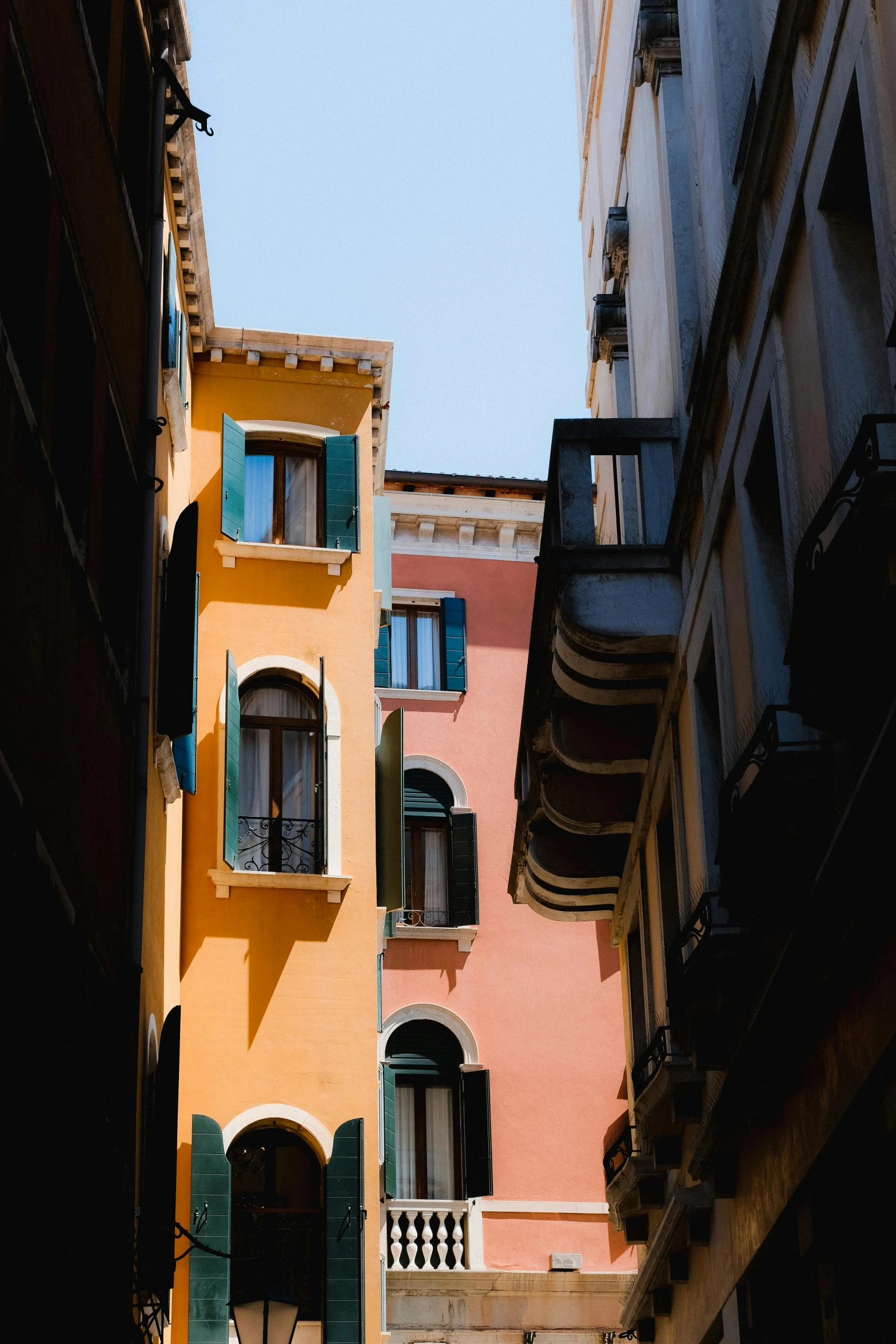 a yellow building with shutters on it and a couple of green doors