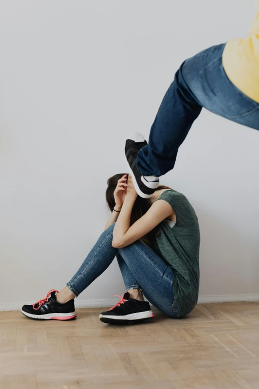 a  sits on the floor and holds his head against a woman's shoulders