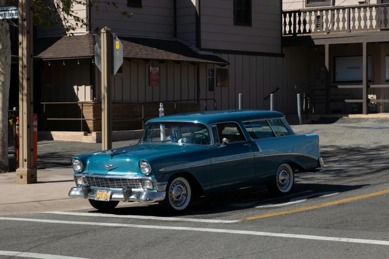 a turquoise vintage car on the side of a road