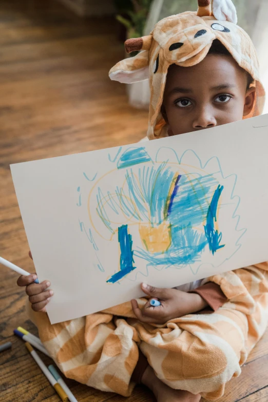 a little girl sitting on the floor holding a drawing