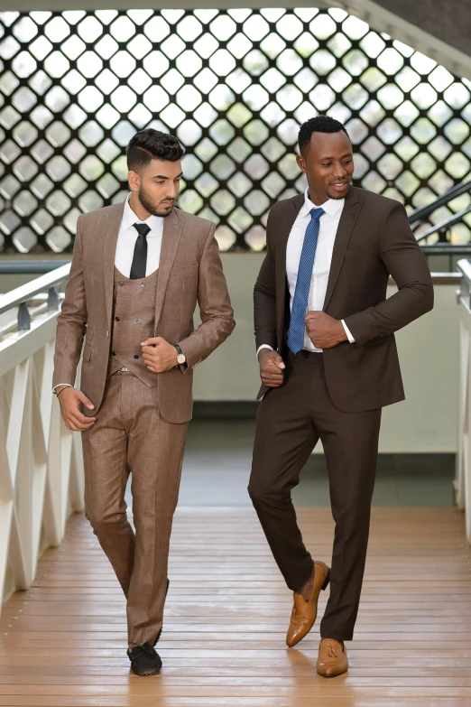 two men in suits are walking across the bridge