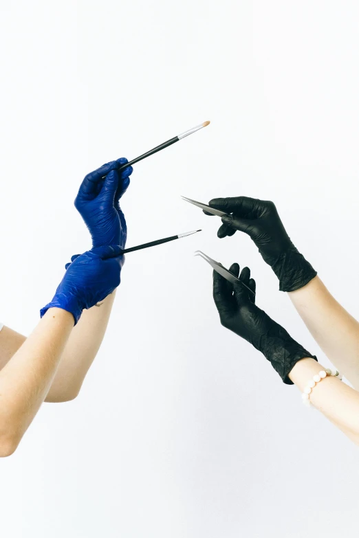 two hands with black gloves are holding some tools