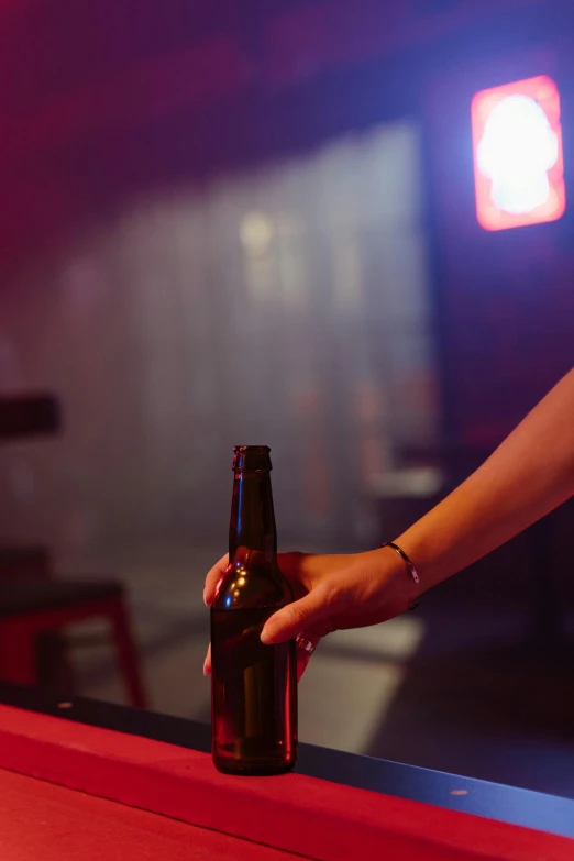 a beer is sitting in the middle of a counter with a person hand reaching out to drink