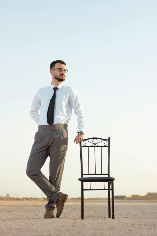 a man with a tie standing near a chair