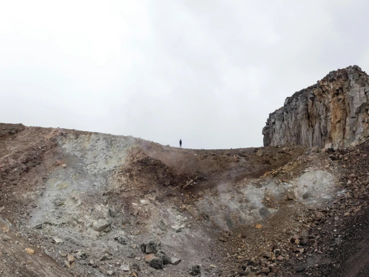 two men standing on a barren hill with a rocky hillside behind them