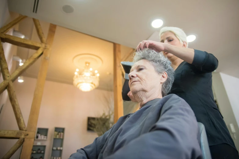 woman doing hair for another woman with blonde hair