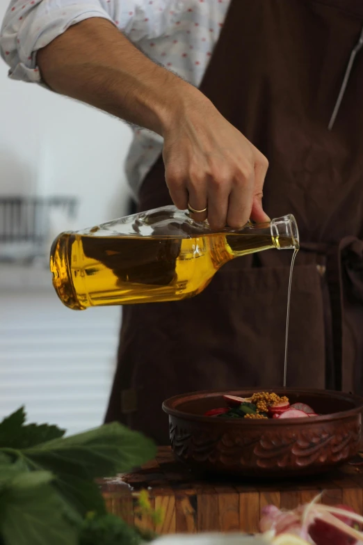 a chef pouring oil on a dish with vegetables