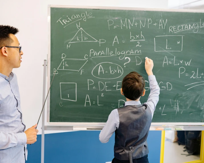 two boys are doing a math lesson on the chalkboard