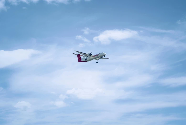 the airplane is flying in the sky over some trees