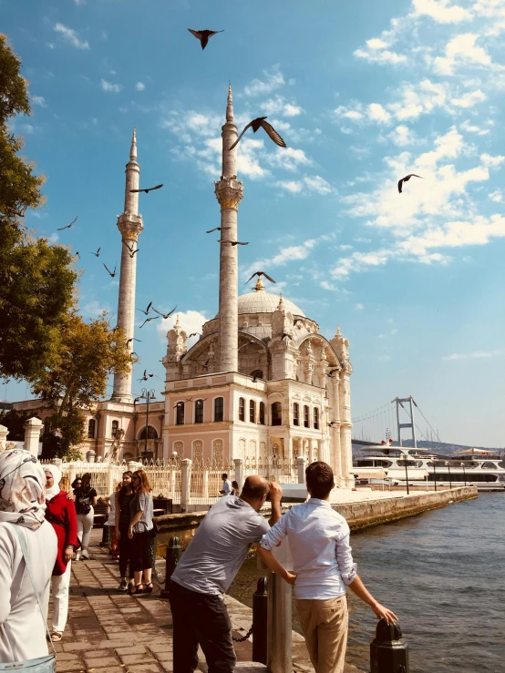 a group of people standing on the water next to a white building