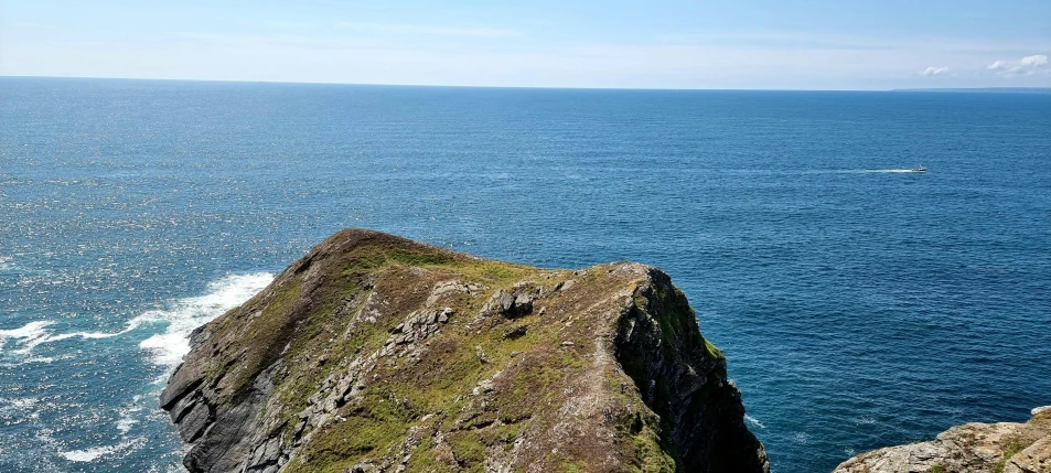 a boat in the water off the coast of a small rocky cliff