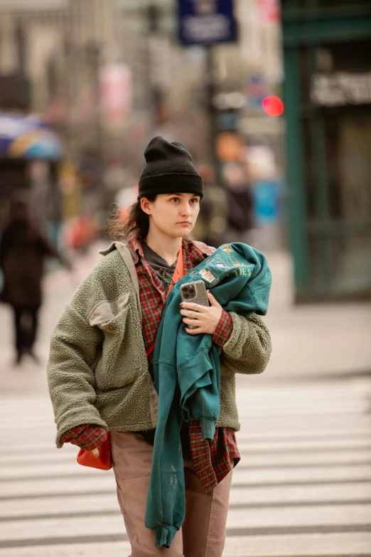 a girl holding a backpack and wearing a cap on the street