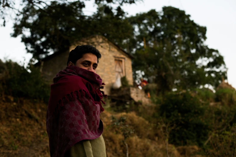 a man in a red coat is standing next to a tree