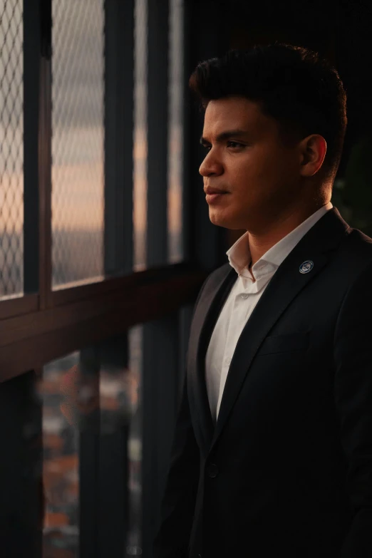 a man in a suit looks out from behind a window