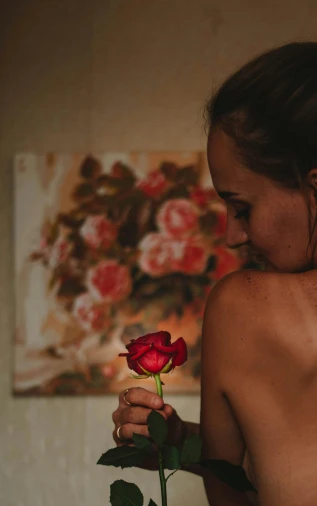 woman smelling a single rose in her bedroom