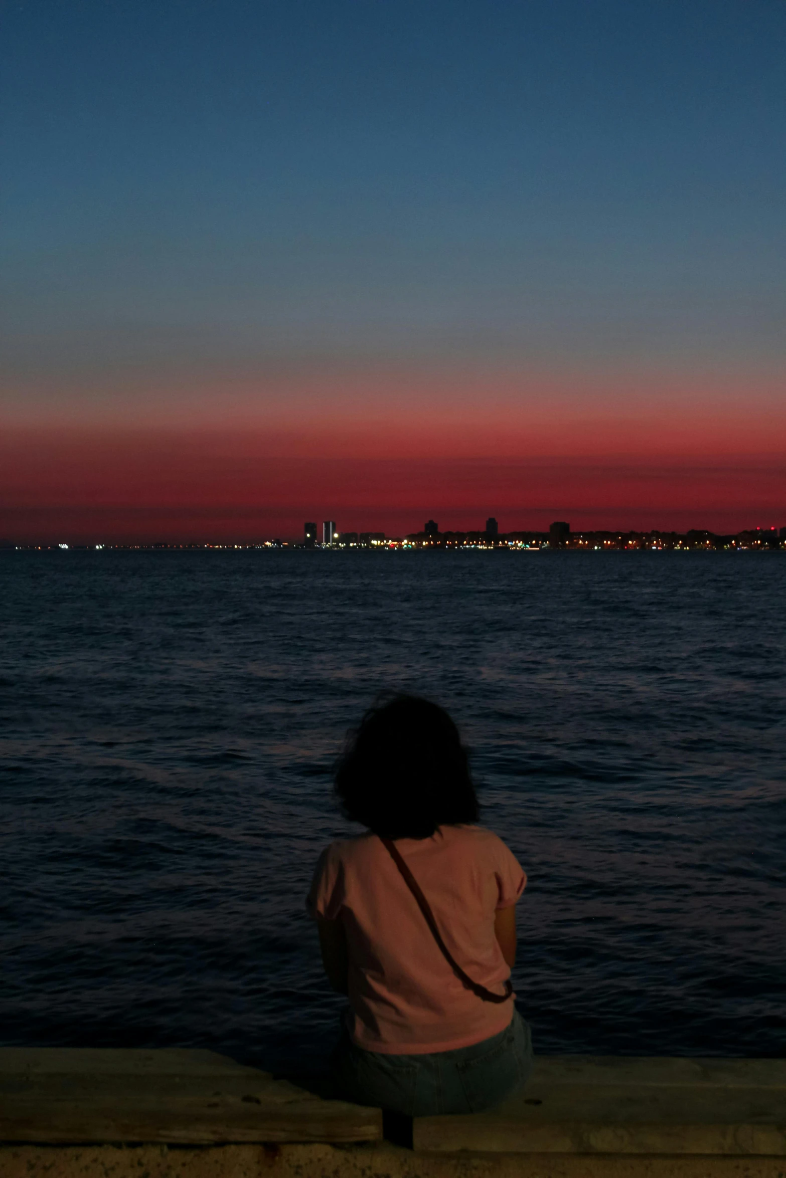 a person is sitting on a dock looking out into the water