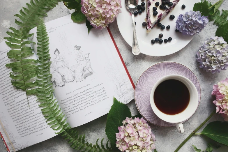 the book is opened and next to a cup of tea with some flowers