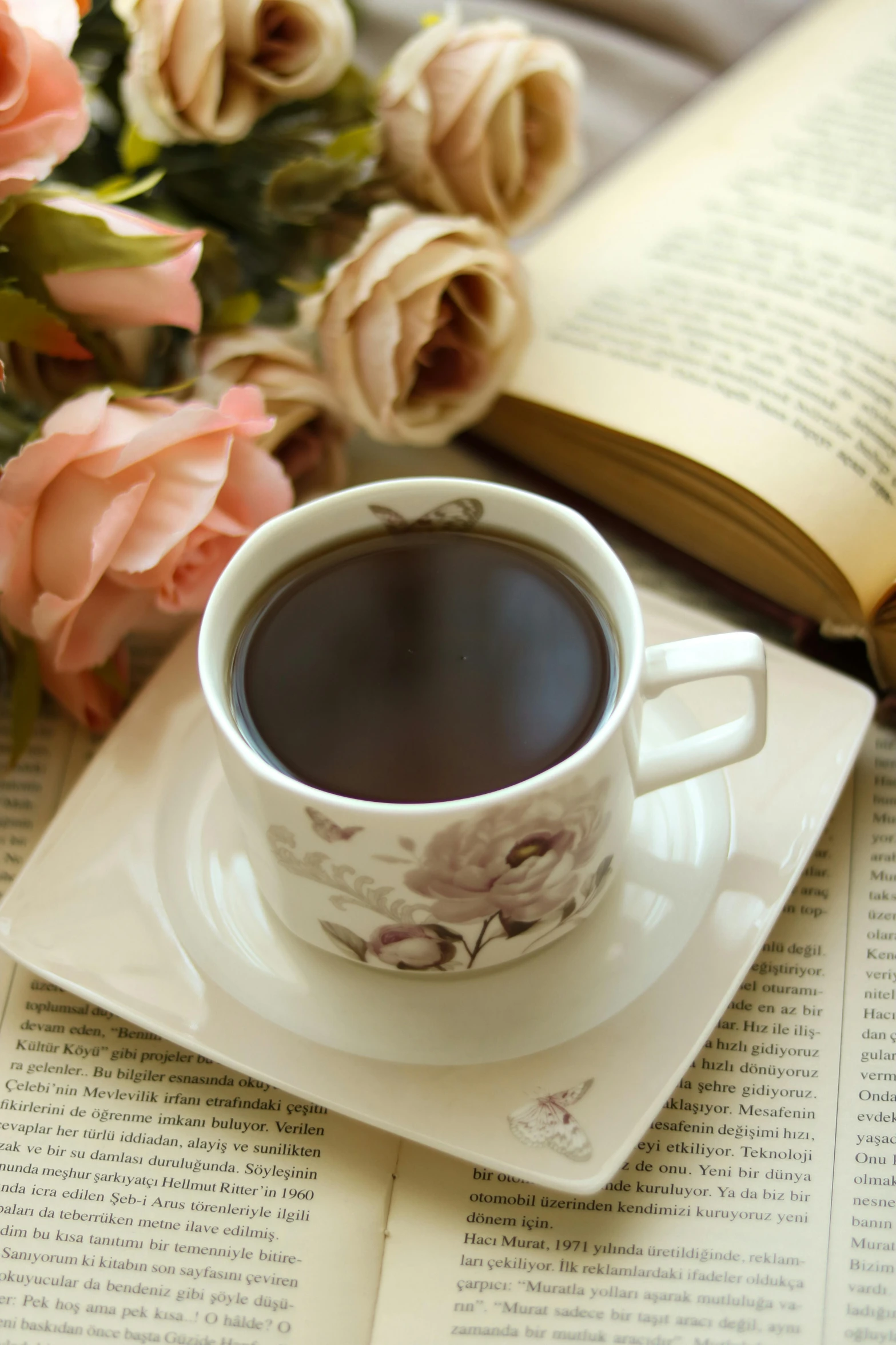 a coffee cup on saucer beside an open book
