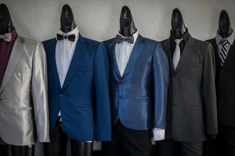 suits and ties on mannequins are all lined up in a row