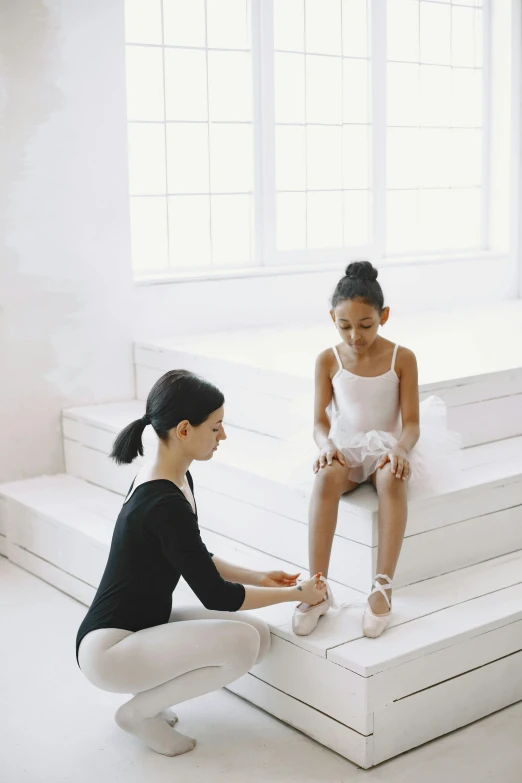 two girls on white steps by window in white room