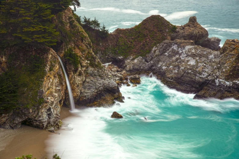 a man swimming into a very pretty beach next to a waterfall