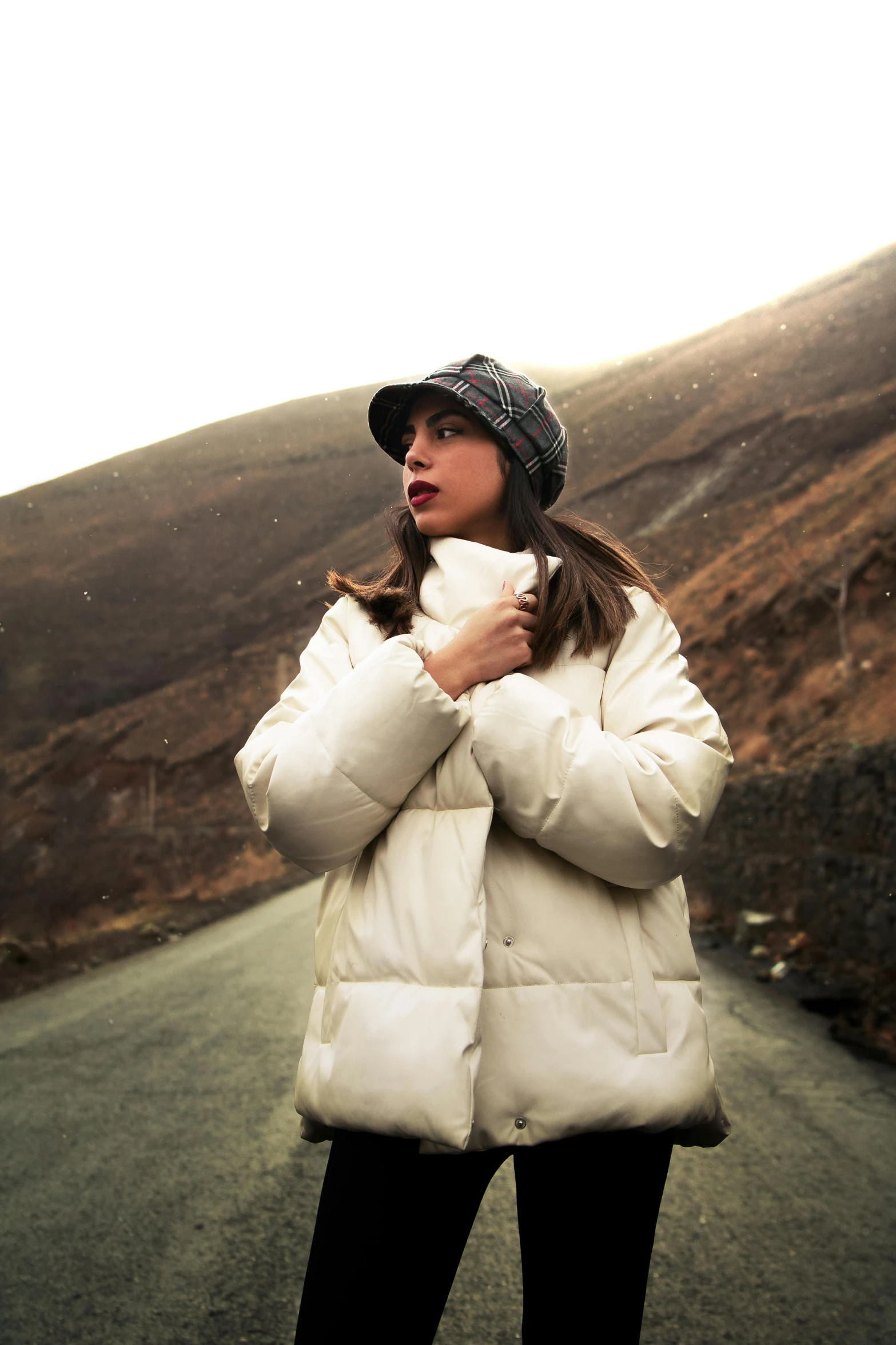 woman standing on side of road while wearing a jacket and scarf