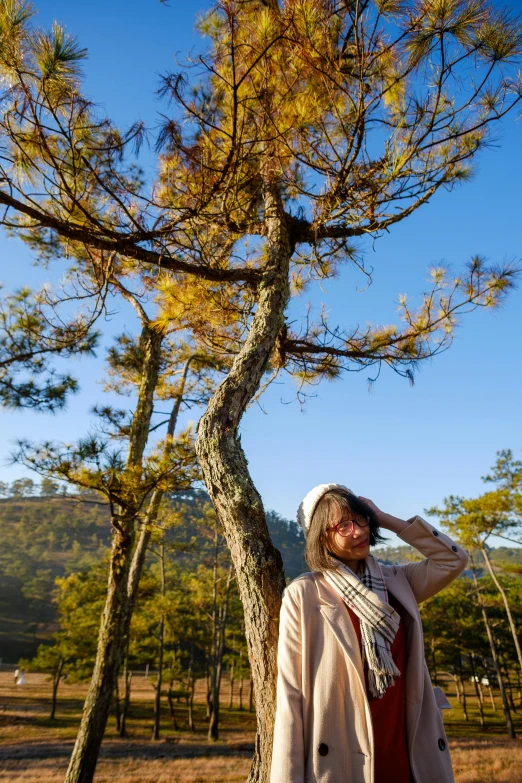 a person leaning against a tree with their hand on their head