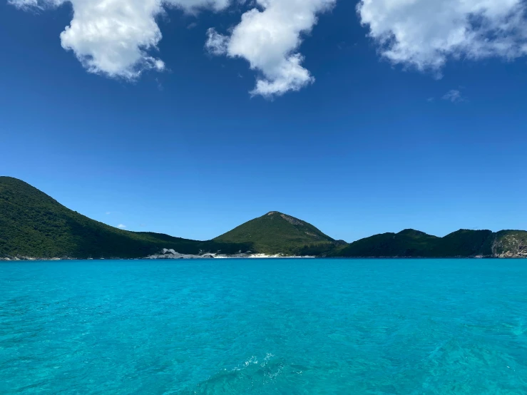 a view of some mountains from the blue water