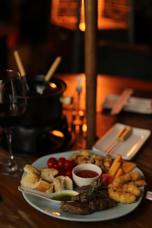 a plate filled with meat and vegetables next to a glass of wine