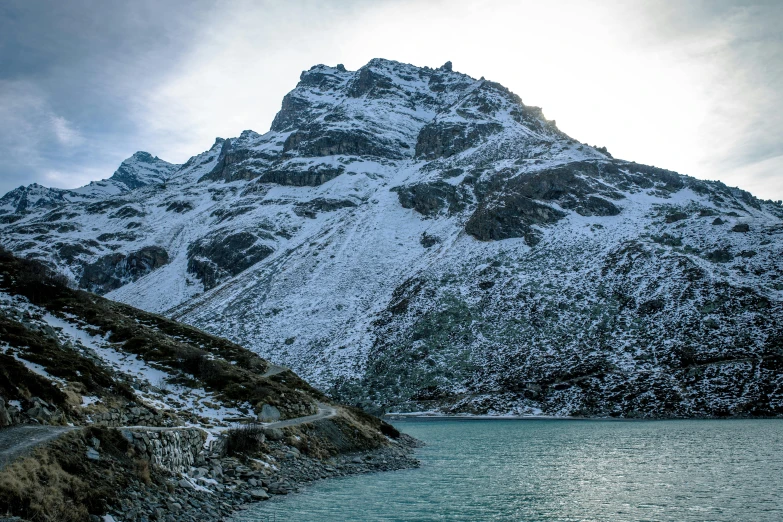 snowy mountain, lake, and road in foreground