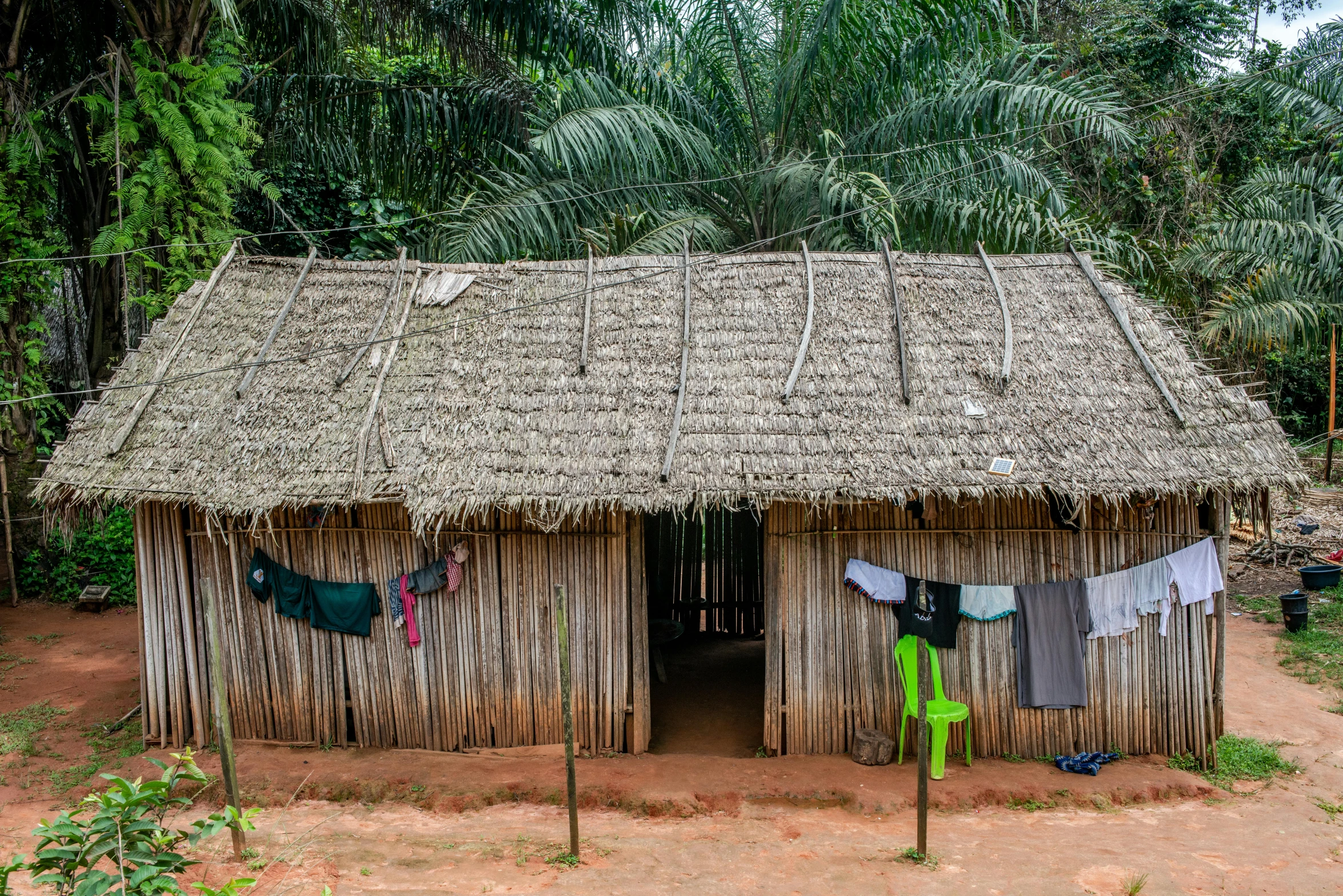 a hut on dirt ground with trees in the background