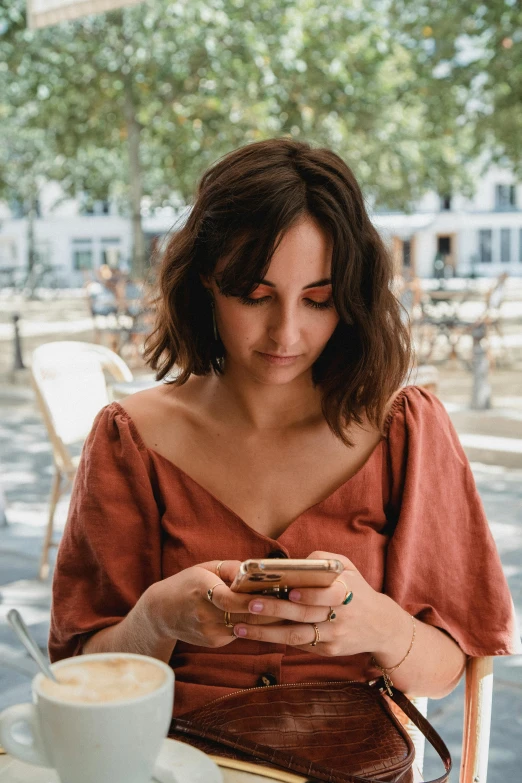 woman at table with a phone, coffee mug and other items