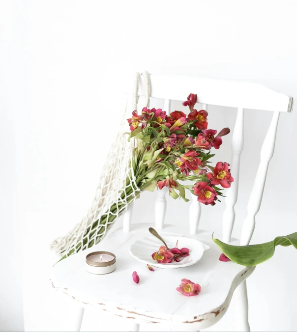 a white chair sitting next to a plate with flowers on it
