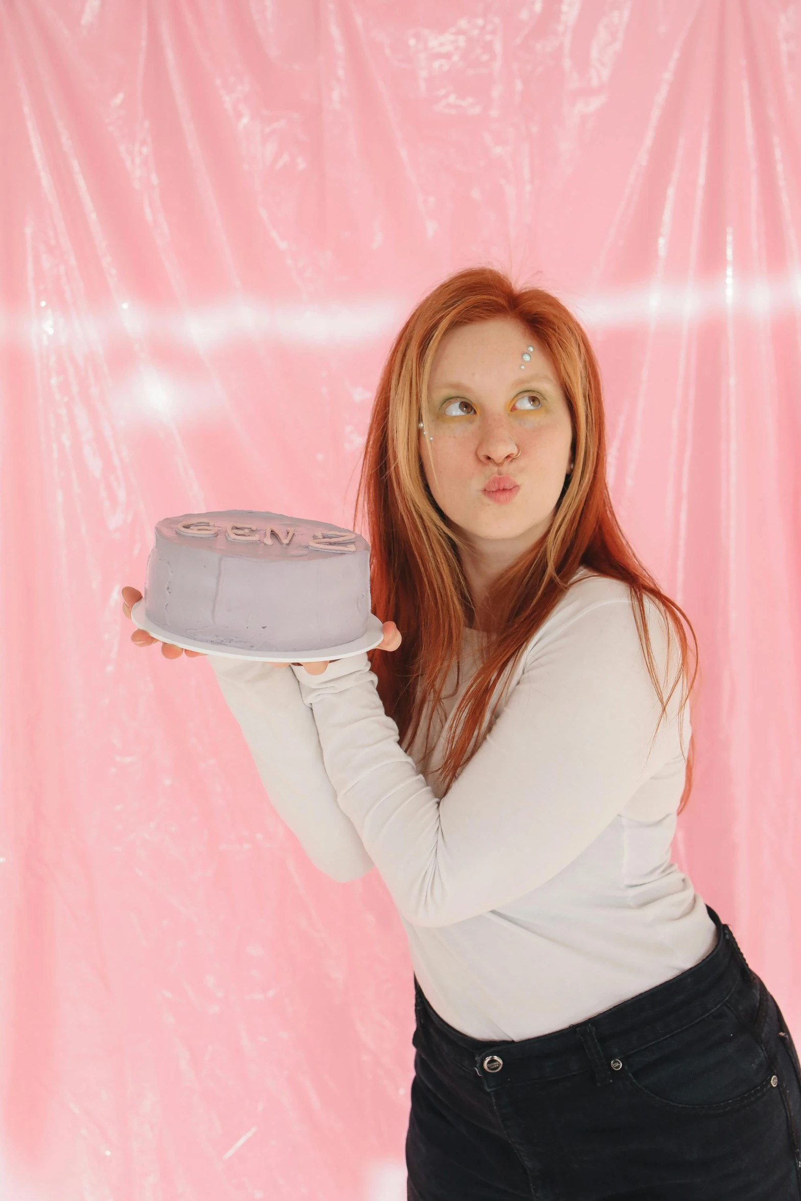 a woman posing holding up a gray cake