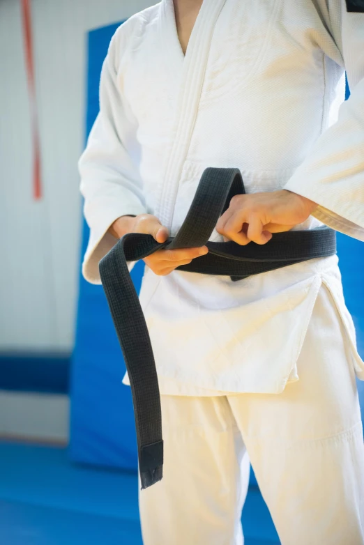 a person wearing a black belt is putting some fabric around