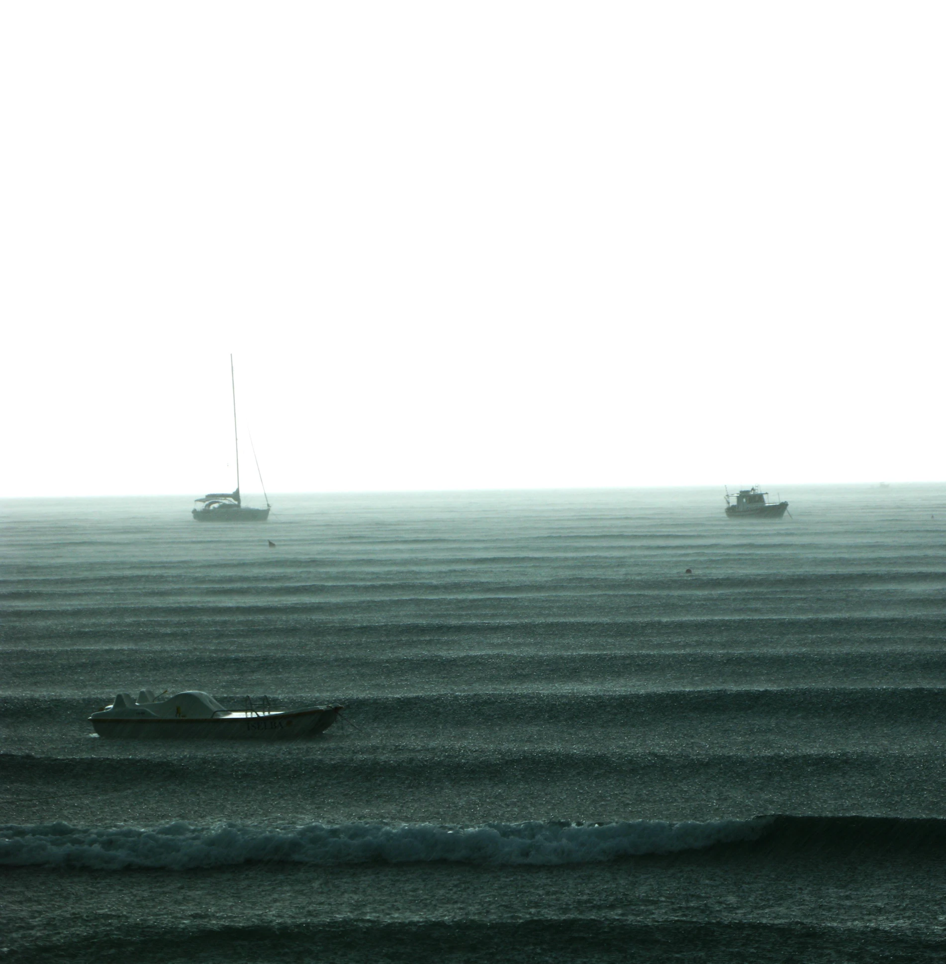 two small boats in the distance at the edge of water